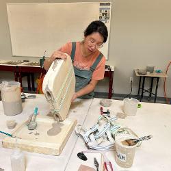 Eliza Au prepares a mold for the kiln.