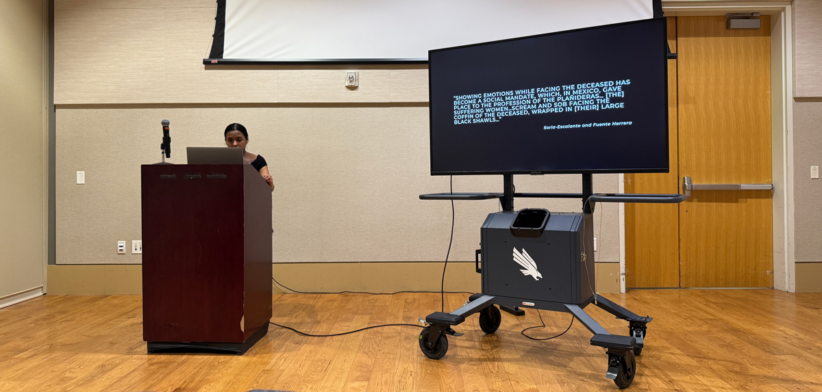 Mercedes Muratalla presents behind a podium.