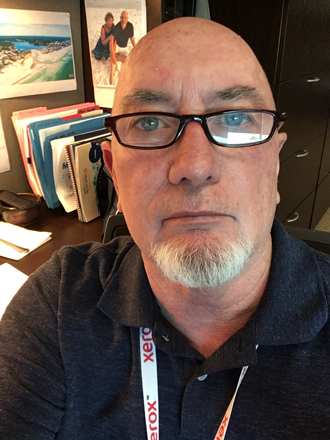 Gary Garrett facing forward. He is bald, wears glasses and a dark shirt.