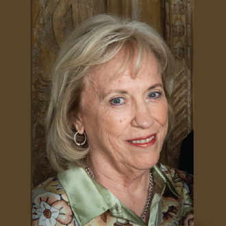 Susan smiling in a 3/4 view. She has blonde hair and wears a printed blouse.