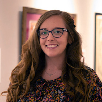 Keela Dooley Marshall smiling, long wavy tendrils, glasses, colorful top