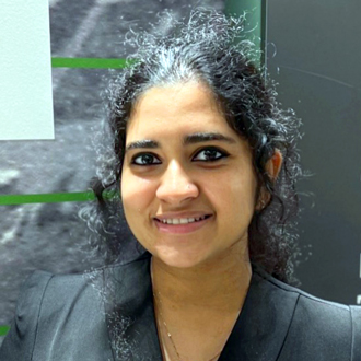 Lasya facing forward and smiling in a gray jacket.