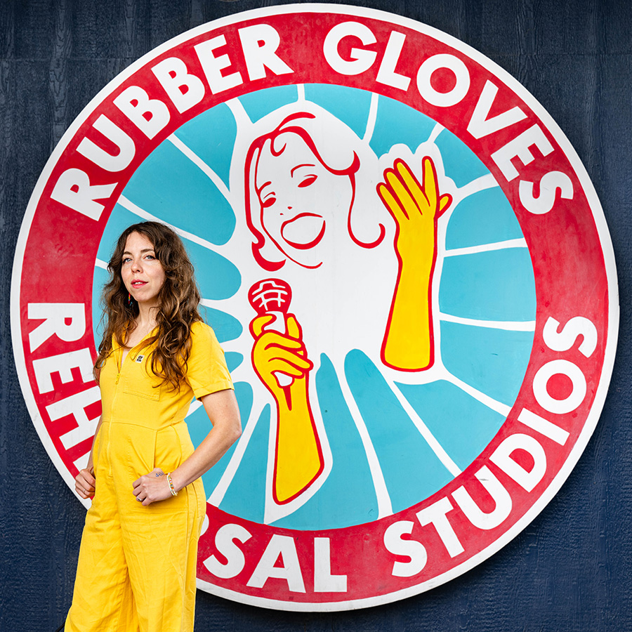Claire Morales stands in front of a large painting of a logo she designed.