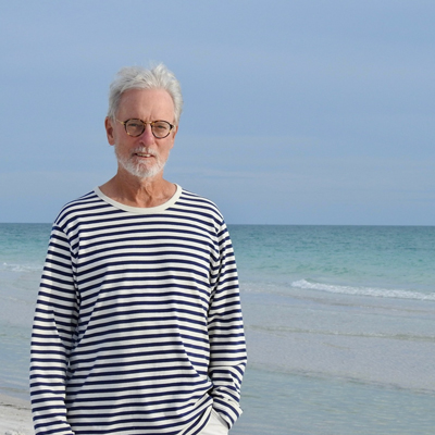 Terry standing on a beach, windblown hair, ocean