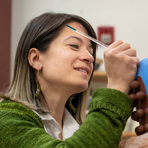 Naomi Peterson painting a ceramic vase