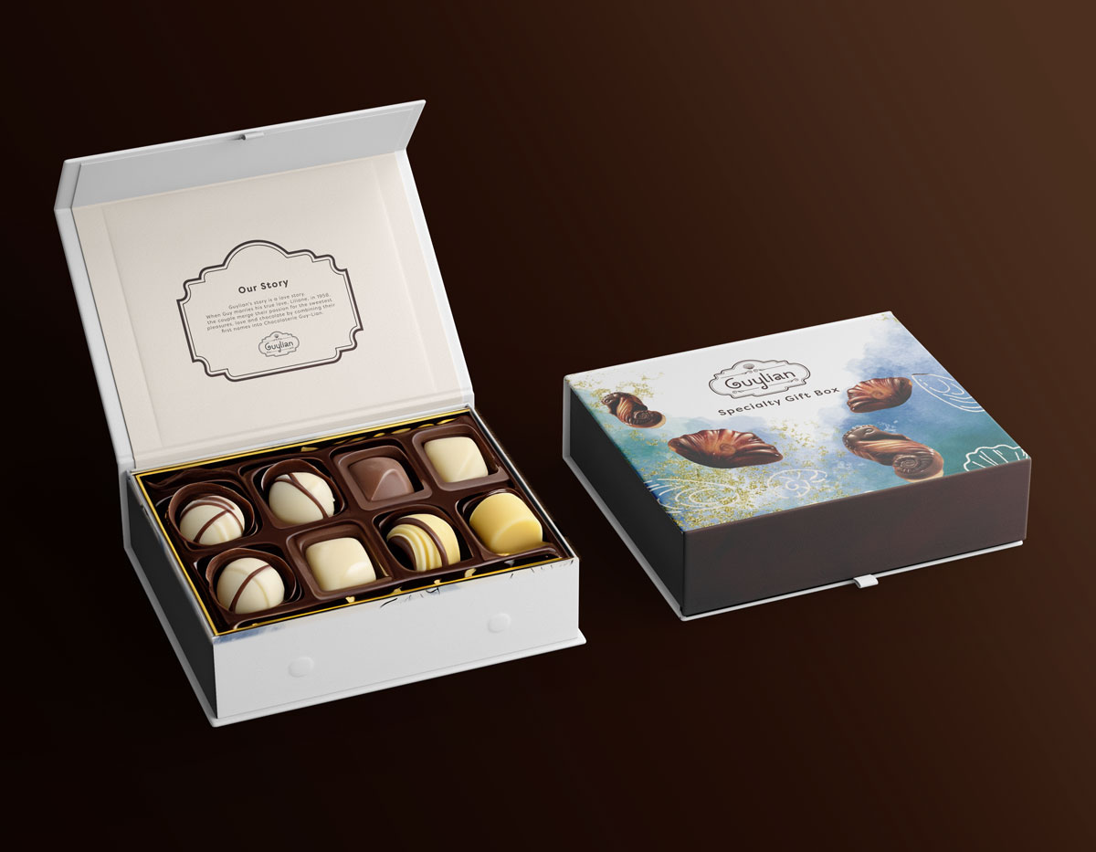 One open box with six decorative chocolates placed inside, as well as a blurb printed on the inside of the lid that reads "Our Story". As well as a second, closed box that is decorated with watercolor reminicent of the color of the ocean.