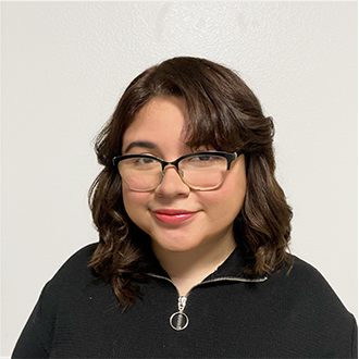 Jazmine is facing forward and smiling. She has brown hair.
