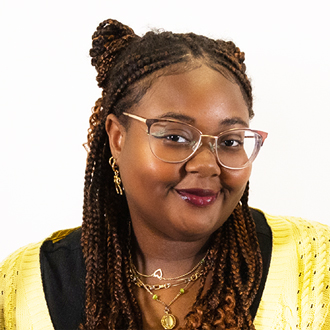 Felicia is facing forward and smiling. She has brown hair and wears a yellow top.