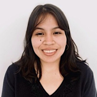 Lesley is facing forward and smiling. She has dark hair and a dark, v-neck top.