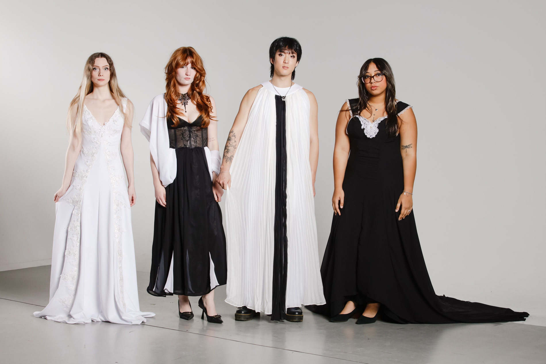 Women and a man wearing black and white evening attire.