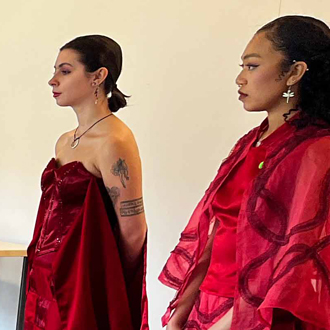 Two fashion models wearing red gowns.