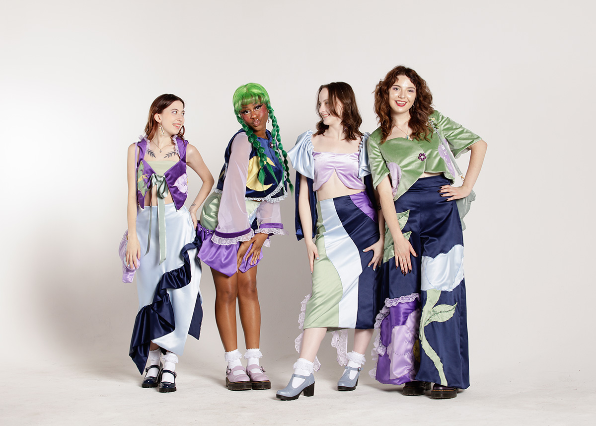 Four models wearing satin and velvet garments with beading, patchwork, and textile painting details. 