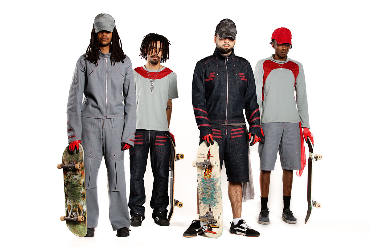 A group of four skateboarders, standing with a white backdrop, each wearing tailored Skateboarding Technical Gear. A dark indigo and gray monotone color palette resembles the “urban streets” and red accents to encase the passion and resiliency of a skateboarder. Denim is used as the outer protective layer and polyester as the sweat-wicking base layer, each bringing protection, ventilation, and comfort to the skateboarder.
