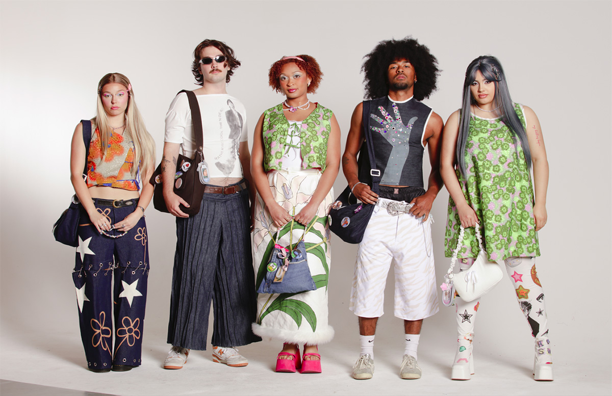   5 models, 3 girls and 2 guys. The first model is a girl wearing an orange top with printed flowers and a pair of pants that have hand-painted white stars and orange flowers. The top is reversible, and the other side is denim. The pants have chains on them so you can turn the pants into shorts. The second model is a guy wearing a white top with a screenprinted model on the front that says “rather be cool than dead”. His pants are denim and made up of pintucks. The third model, a girl, has a green top with printed flowers that are tied together. She has a skirt that is tied together and has hand-painted lilies on the front. The fourth model is a guy wearing a denim top with a hand etched on the front that is bedazzled. He is also wearing jorts that have tiger stripes etched on them. The fifth model, a girl, is wearing a dress that is also green with printed floors. She is also wearing leggings that have a custom printed fabric. Each model has a bag that was personalized for them.   