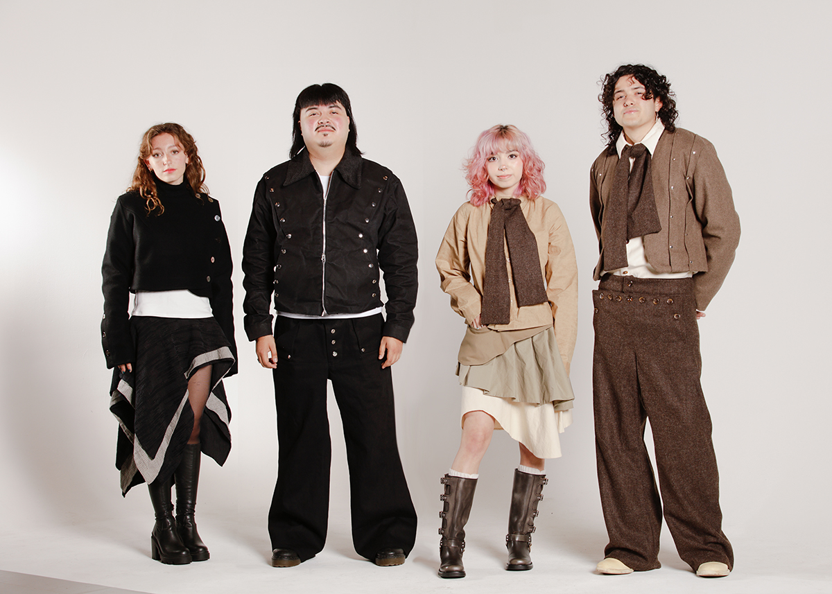 Four models wearing the “Skin In Stiches” collection in front of a white backdrop. The looks are split into two color palettes; one features monotone colors such as white and black, while the other uses earthier tones like brown, beige, and greens. The collection uses layering to showcase the texture of the natural fibers used for the fabrics. 
