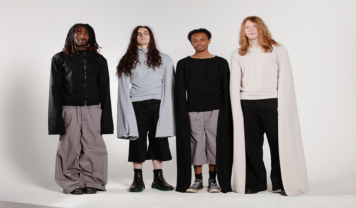 4 models in black, white, and grey with sweater and jacket-like tops, elongated sleeves, as well as oversized and flared denim bottoms.