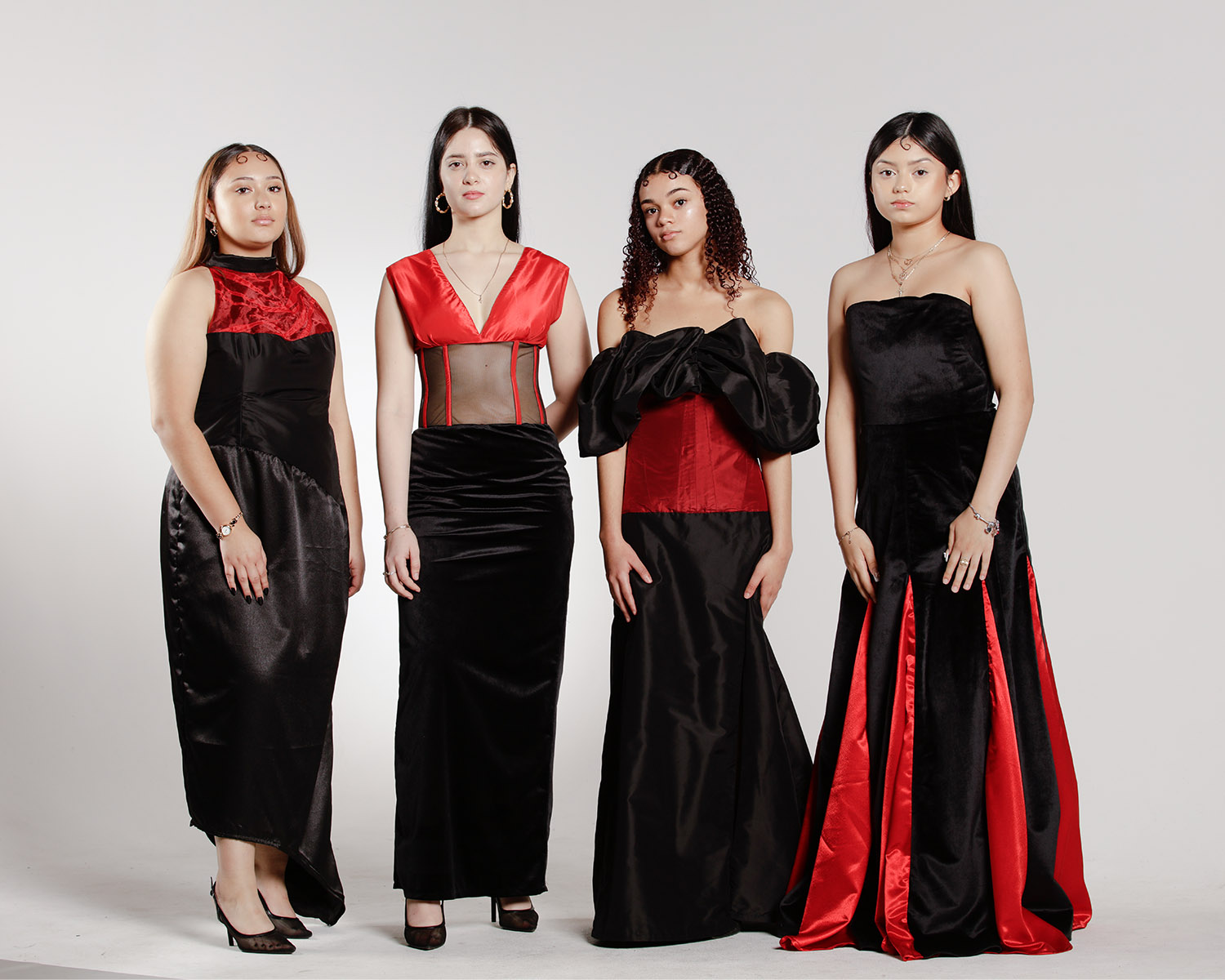 There is four models wearing black evening dresses with a pop of red. 