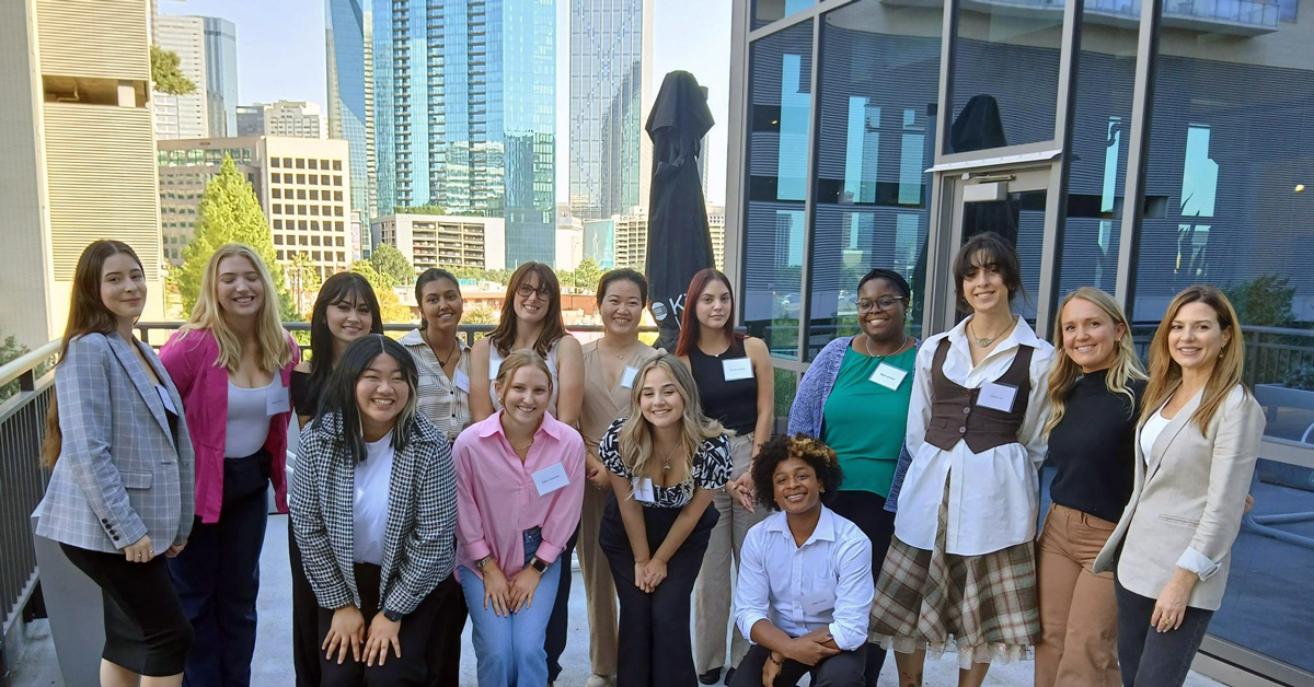 Group of students and Kimball representatives outdoors in a high rise building with other skyscrapers in the background.