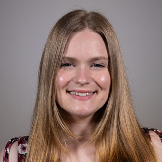 Miranda is facing forward and smiling. She has long, blonde hair.
