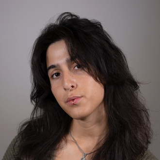 Violeta is facing forward with her head tilted to her right. She has brown hair and wears a necklace.