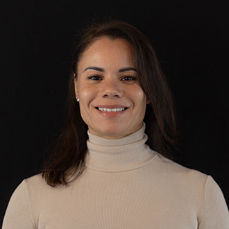 Sherena is facing forward and smiling. She has long, dark hair and wears a cream top.