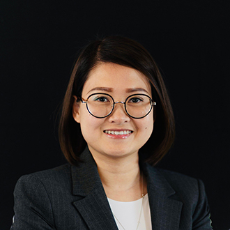 Alice is facing forward and smiling. She has short dark hair and wears a black top.