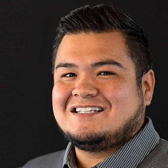 Jonathan is facing forward and smiling. He has short dark hair and wears a black and white top.