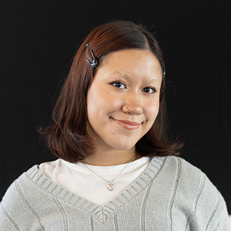 Sofia is facing a three-quarter view and smiling. She has medium-length dark hair and wears a grey top.