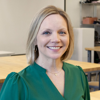 Rachel Black is facing forward and smiling. She has blonde hair and wears a green top.