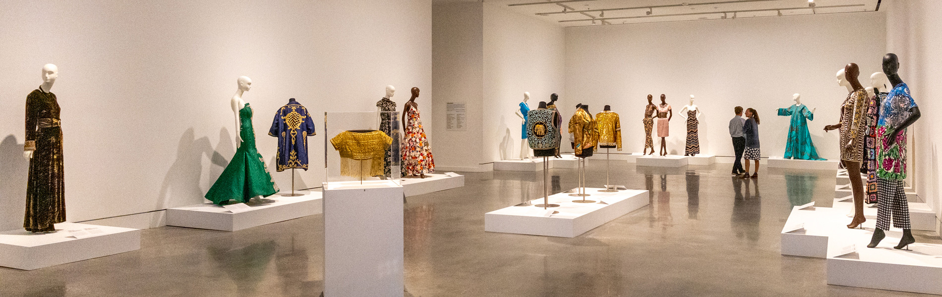 Wide view of a gallery with about 16 gowns on mannequins.