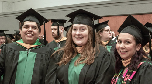 Three students in academic regalia before commencement ceremonies.