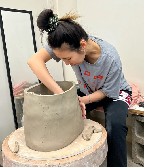 Jihye Han working at a potter's wheel with a large clay pot.