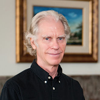 Robert Jessup facing forward and smiling. He has white hair and wears a black shirt.