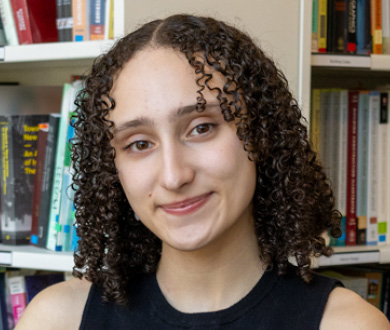 Hannah Matthews is facing forward and smiling. She has brown curly hair.