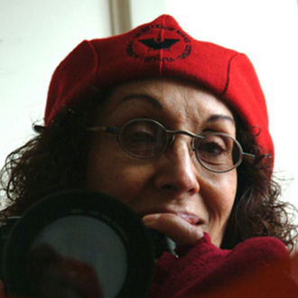 Celia Alvarez Munoz is facing the camera, smiling and wearing a red beret and glasses.