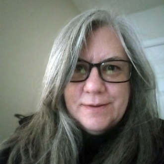 Jennifer Way is facing foward and smiling. She has long silver hair and wears a dark top.