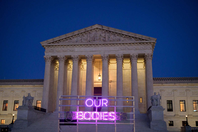 Supreme Court Bldg with "our bodies" in pink neon light