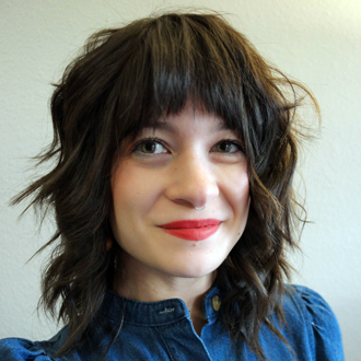 Naomi Peterson facing forward, smiling, shoulder-length dark hair, denim shirt