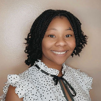 Janay facing forward, smiling, short black hair, dotted shirt