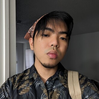 Jeremy wearing a dark printed shirt and a brown bandana