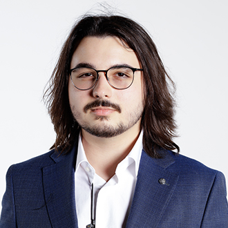 Chance Gaston facing forward, shoulder-length hair, glasses, mustache and beard, blue jacket, white shirt