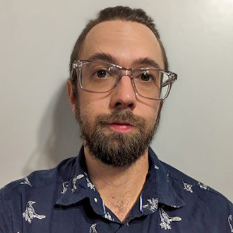 Noah facing forward, short brown hair, glasses, beard and wearing a black-and-white shirt.