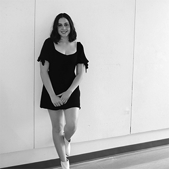 Noelle Hayes, portrait, wearing a dress, standing against a wall