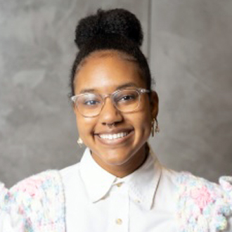 Headshot of Ariana Hill in pink crocheted vest.