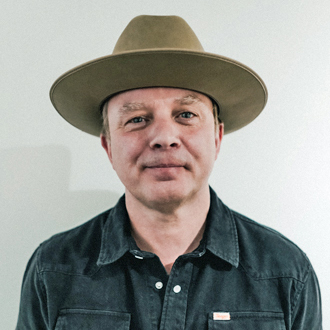 Matt Klug facing forward smiling, wearing a hat Panama hat