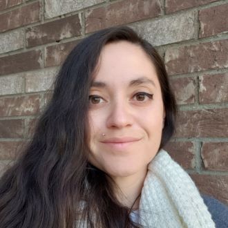 Headshot of Ranee Leider smiling in front of brick wall.