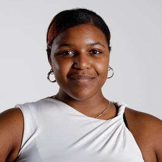 Briona facing forward, smiling, gold earrings, white top