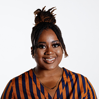 Tatynna facing forward, smiling, dark brown hair tied up, orange and blue striped shirt