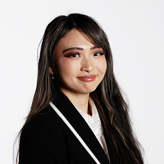 Winnie, facing forward, wavy dark brown hair, black jacket with a white shirt 