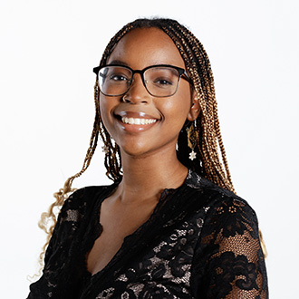 Darria facing forward with glasses, brown braided hair, black netted dress 